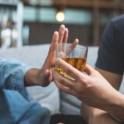 Person putting their hand up to a glass of alcohol