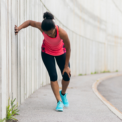 woman holding knee in pain while on a run